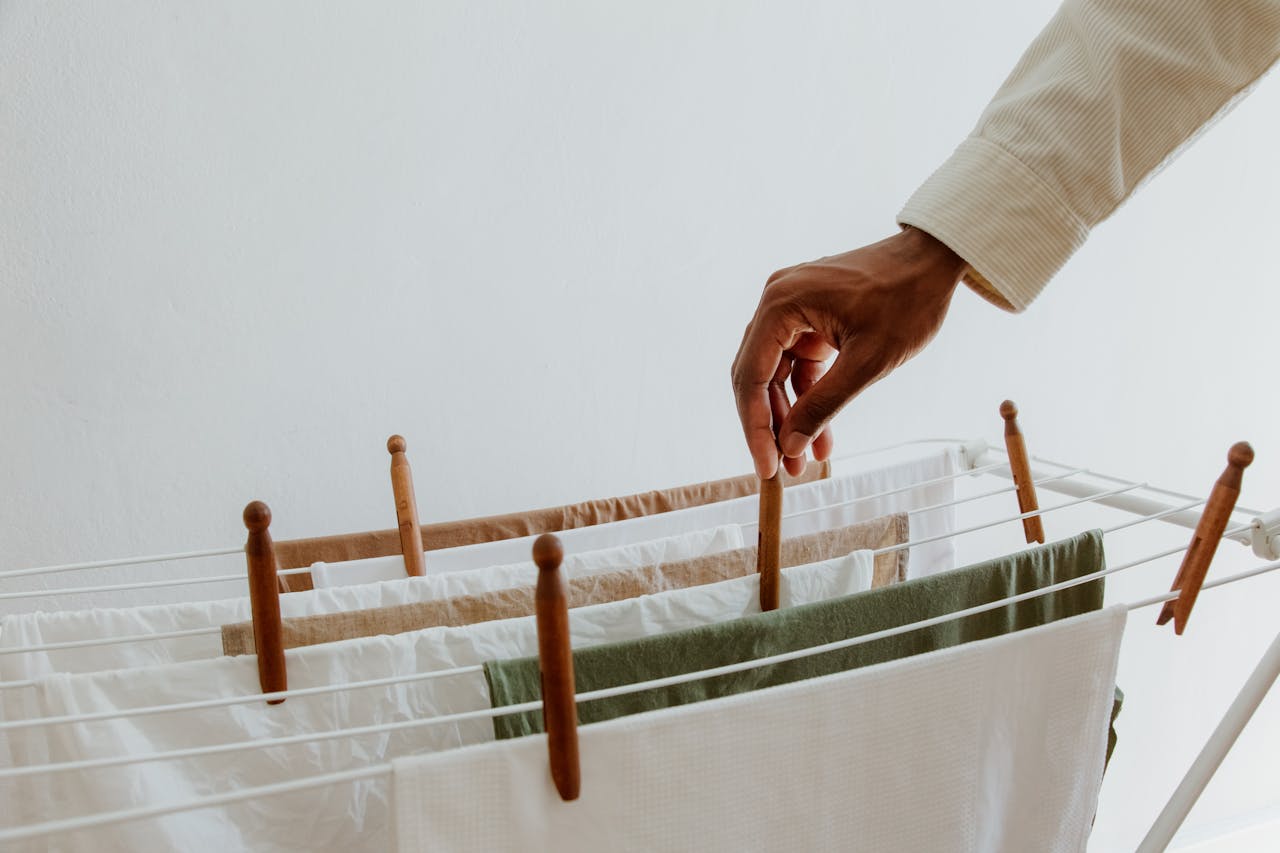services-03 Close-up view of a hand placing clothes on a drying rack indoors, emphasizing freshness and hygiene.